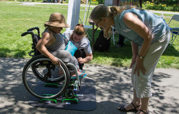 A woman in a wheelchair receives assistance using the Lilly Pad portable scale