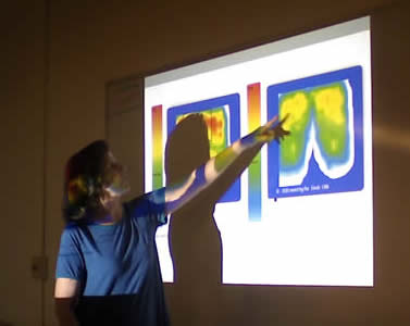 A woman points to pressure mapping images on a projected screen. 