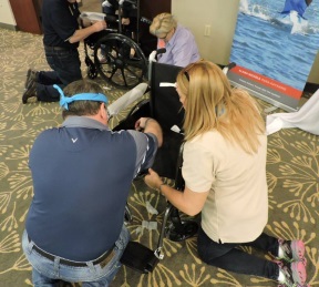 Several adults kneeling on carpeted floor to build wheelchairs.