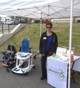 Woman standing next to the REquipment outreach table with pediatric mobility devices. 