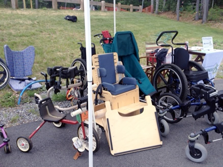 A collection of pediatric mobility, seating and positioning equipment next to the REquipment outreach table.
